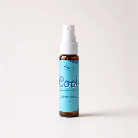 A bottle of Oboo Cool Spray for Hot Flashes, featuring a light blue label and white spray nozzle on an amber glass bottle, set against a plain off-white background.