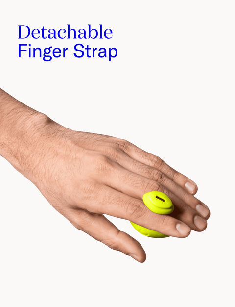 Hand wearing a yellow vibe with detachable finger strap on a white background