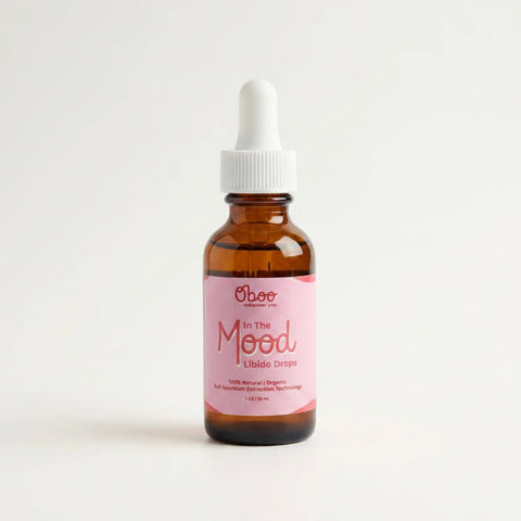 An amber glass dropper bottle of Oboo 'In The Mood' Libido Drops with a pink label and white dropper cap, set against a clean white background.