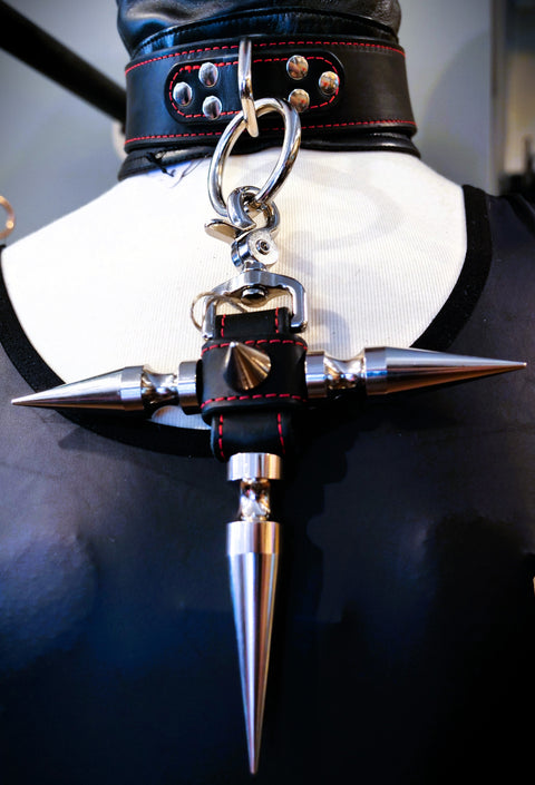 A gothic-style spiked collar charm with silver metal spikes, black leather trim, and red stitching, displayed on a black mannequin torso.