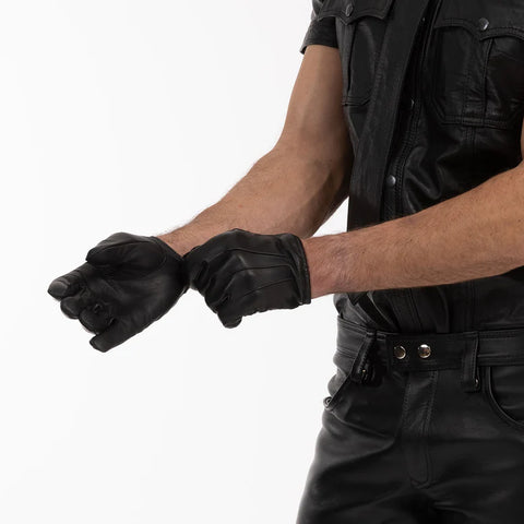 Person wearing black leather gloves and a black leather outfit on a white background