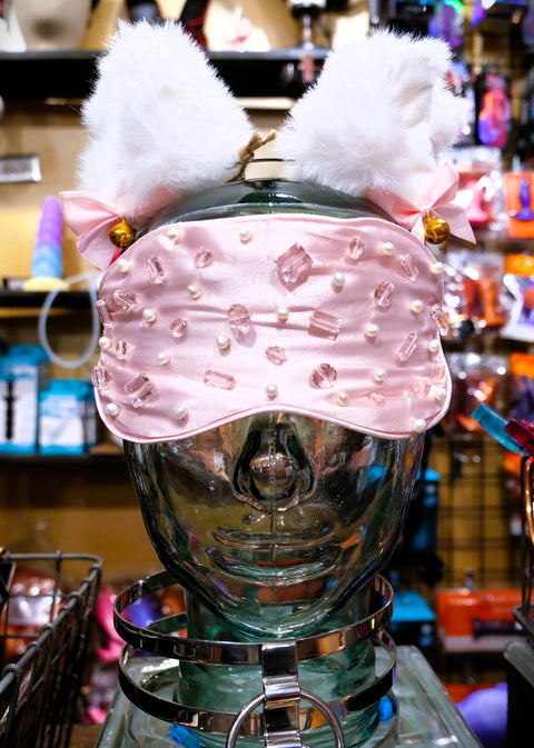 Pink satin blindfold with pink crystal and pearl embroidery on a glass head with white fluffy cat ears