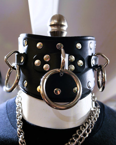 Black leather posture collar with silver rings and chains on a mannequin.