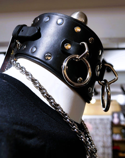 Black leather posture collar with silver studs, rings and chains on a mannequin.