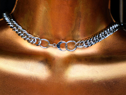 Silver chain necklace on a person's neck with a blurred background