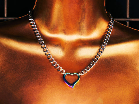 Necklace with a heart-shaped pendant on a person's neck against a dark background