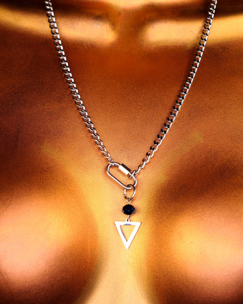 Close-up of a necklace with a triangle pendant on a person's chest.