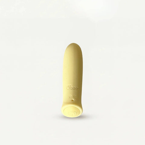 A single pale yellow silicone personal massager standing upright on a light gray background. The product features the debossed brand name 'Oboo' and small control buttons on its lower base.