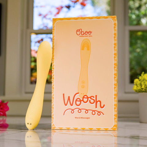 Oboo Woosh wand massager with packaging on a blurred outdoor background