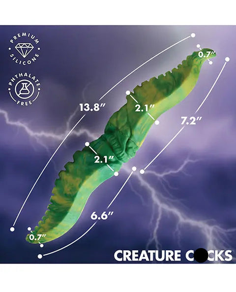 A green and yellow marbled novelty product shown diagonally on a purple storm-cloud background with white lightning and overlaid measurement lines and text indicating dimensions. White text at the bottom reads 'CREATURE C*CKS', and circular badges at the upper left say 'PREMIUM SILICONE' and 'PHthalate FREE'.