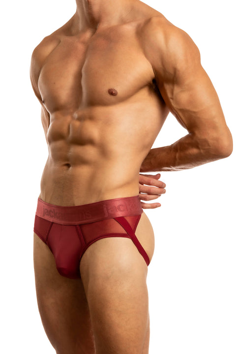Man wearing a red mesh jock brief underwear on a white background